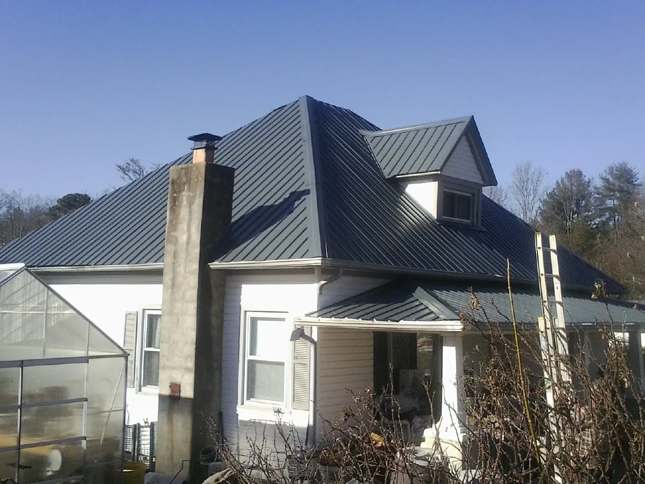 Dark blue standing seam metal roof on a white farmhouse with dormer — Slate & Tile Roof Repair by Roofing Brothers in East Rutherford