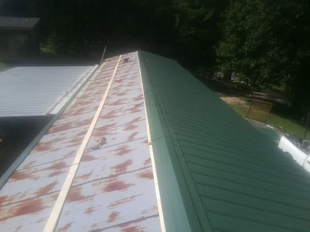 Old rusted panels beside newly installed green metal roofing — Wind Damage Roof Repair by Roofing Brothers in East Rutherford