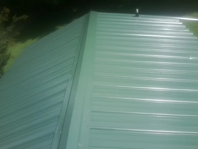 New green metal panels meeting at the ridge of a roof — Flat Roof Repair work by our crew in East Rutherford