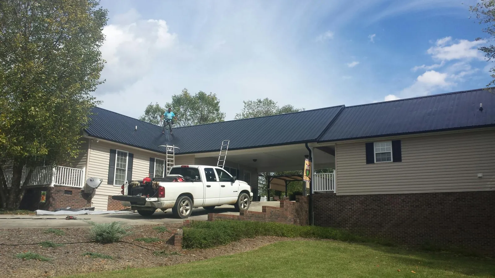 Black metal roof over a home and attached breezeway with ladders set in East Rutherford