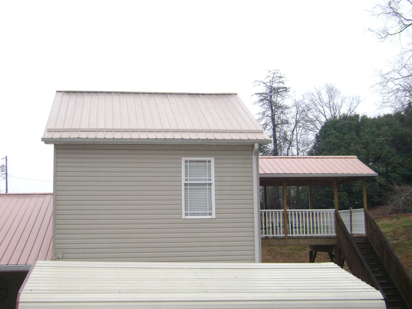 Tan metal roofs on a two story addition and attached porch, from a Roof Replacement job in East Rutherford