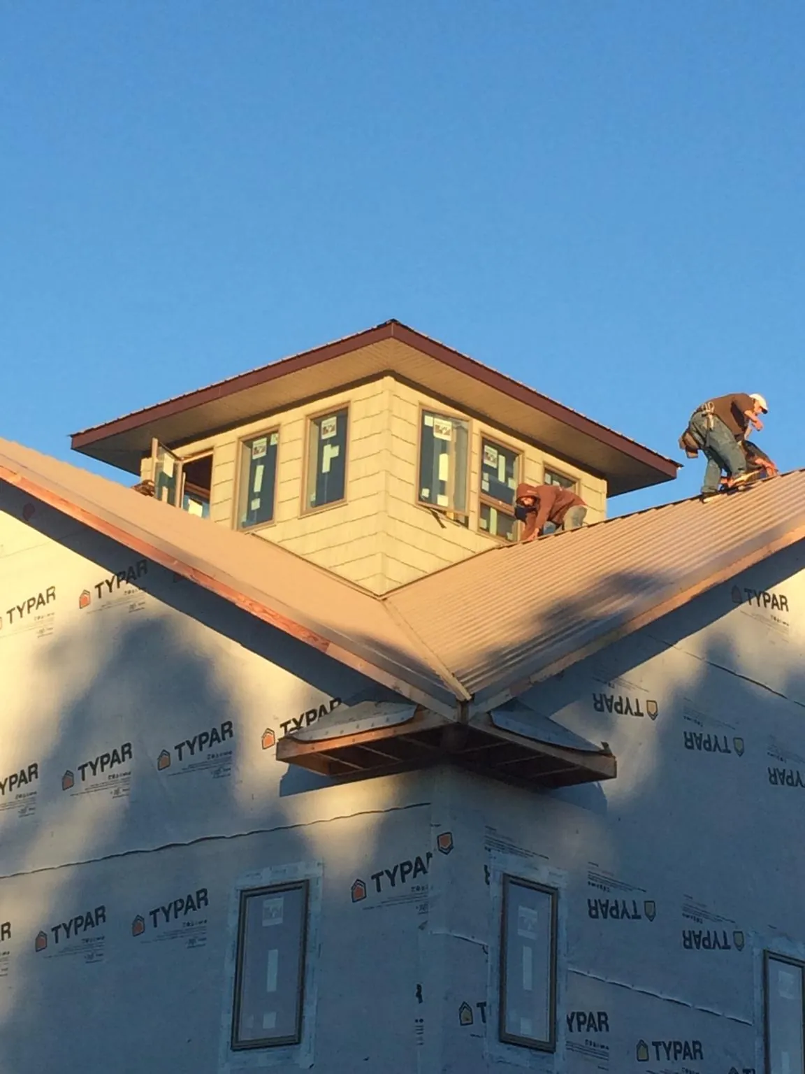 Roofers working around a rooftop cupola on a new metal roof at sunset — Roof Waterproofing in East Rutherford by Roofing Brothers